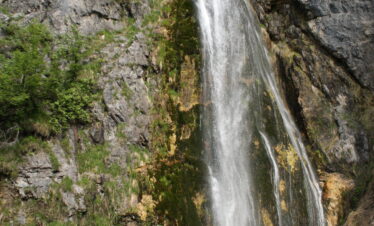 Grunas waterfall cascading through forested gorge in Theth National Park