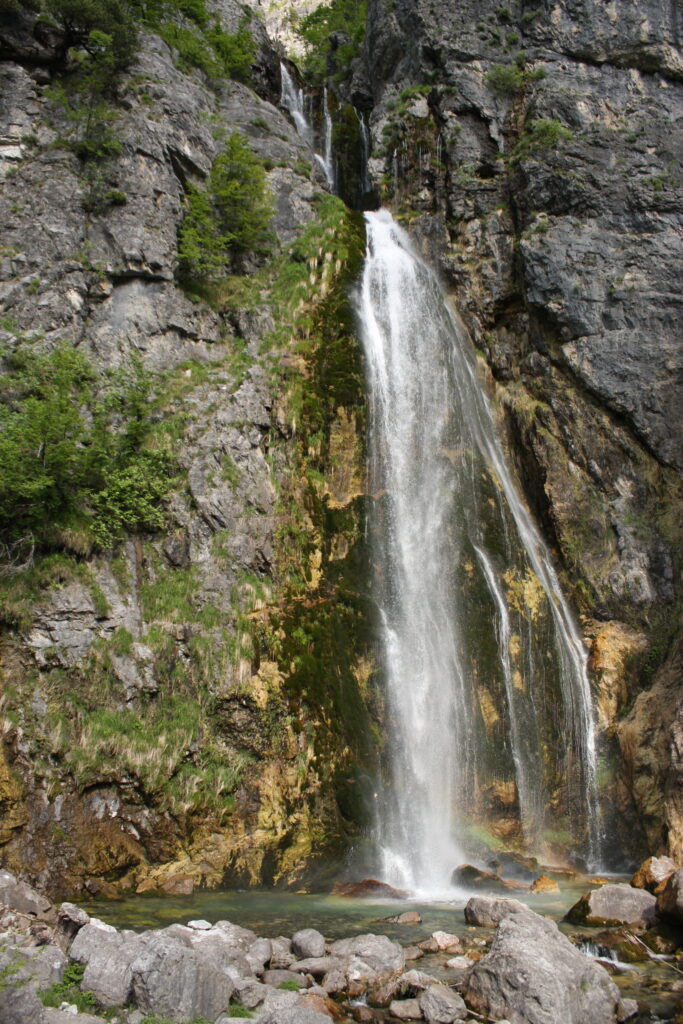 Grunas waterfall cascading through forested gorge in Theth National Park