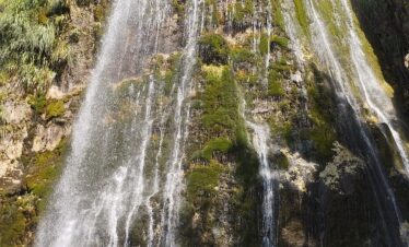 Grunas waterfall cascading through forested gorge in Theth National Park