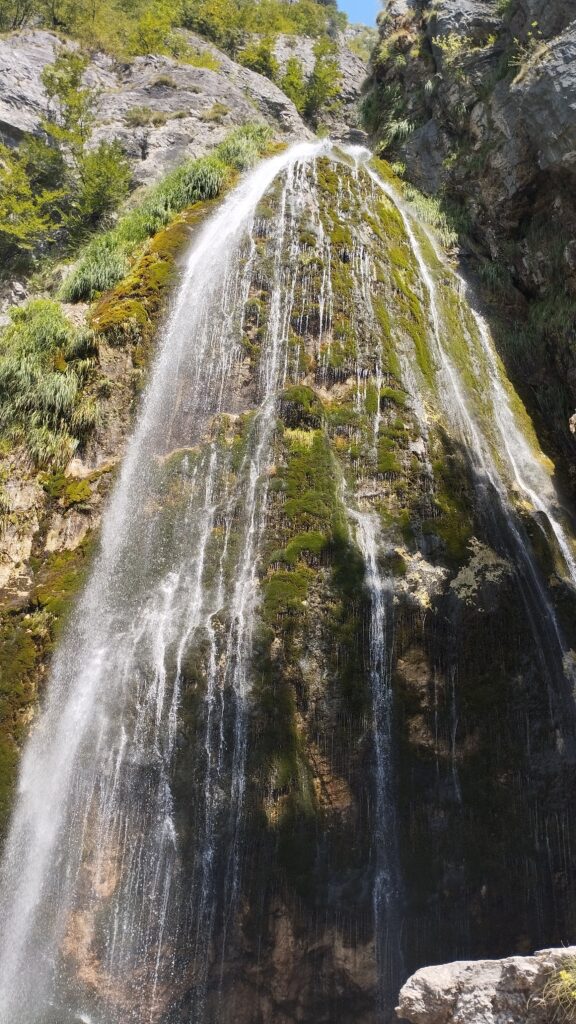 Grunas waterfall cascading through forested gorge in Theth National Park