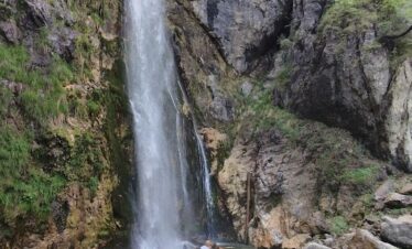 Grunas waterfall cascading through forested gorge in Theth National Park